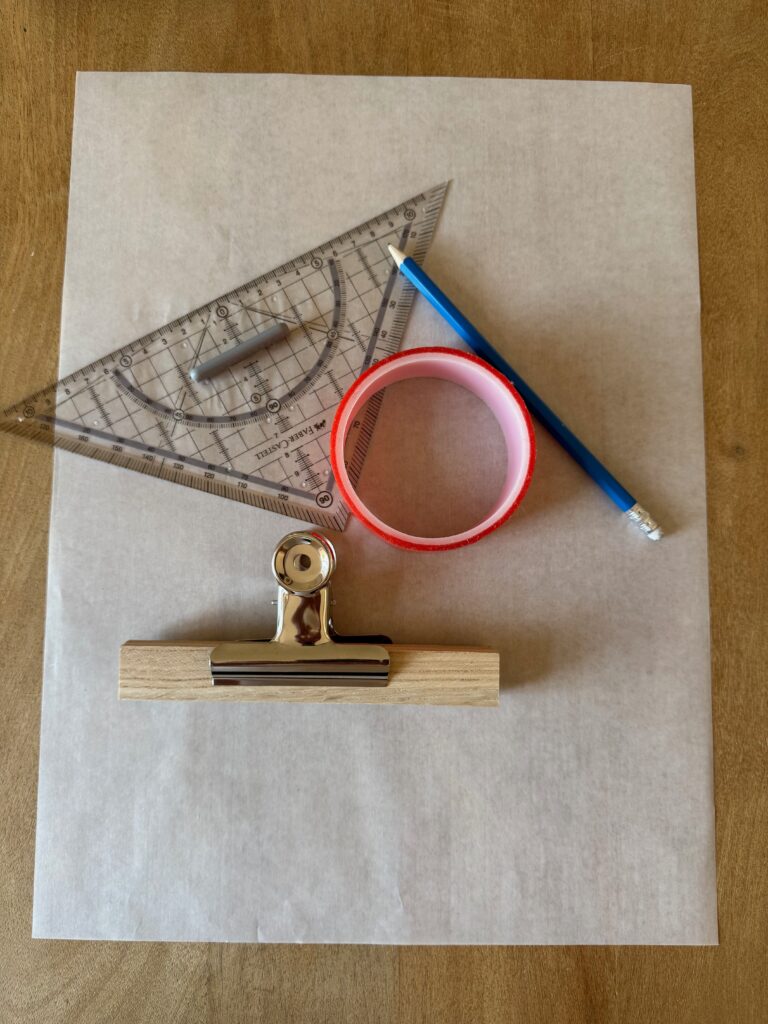 Holzklötzchen mit Klemme, Geodreieck, Bleistift und Klebeband